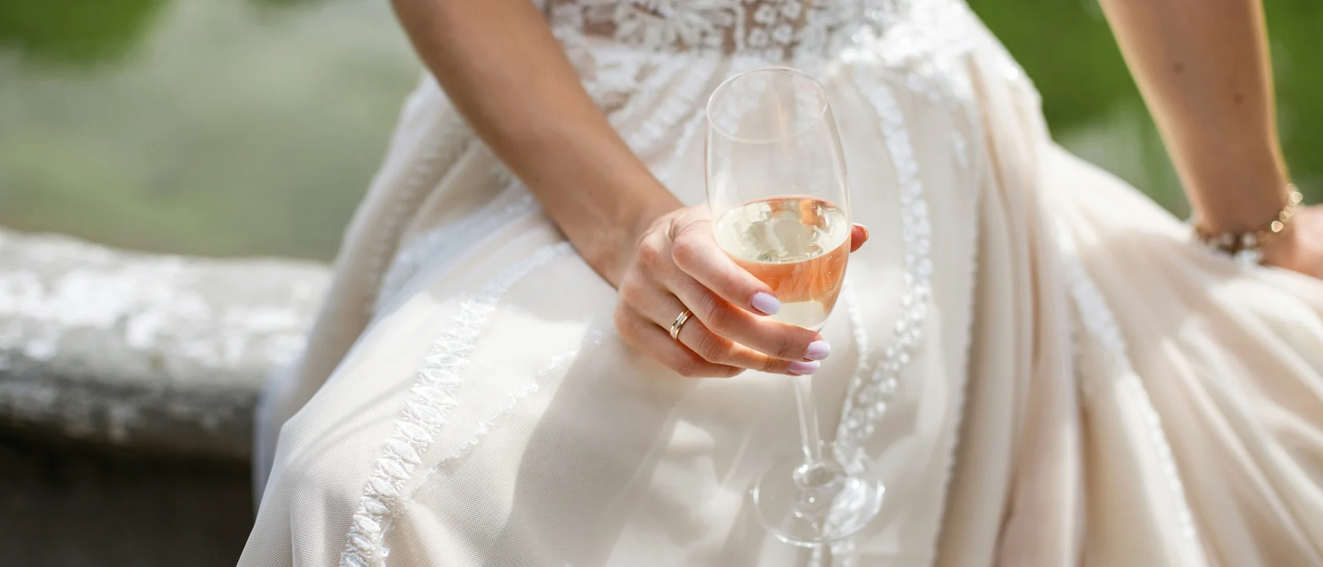 Frau im Brautkleid hält ein Champagnerglas