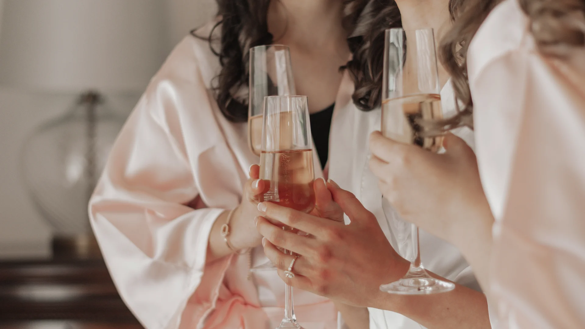 Frauen in seidigen Bademänteln stoßen mit Champagnergläsern an
